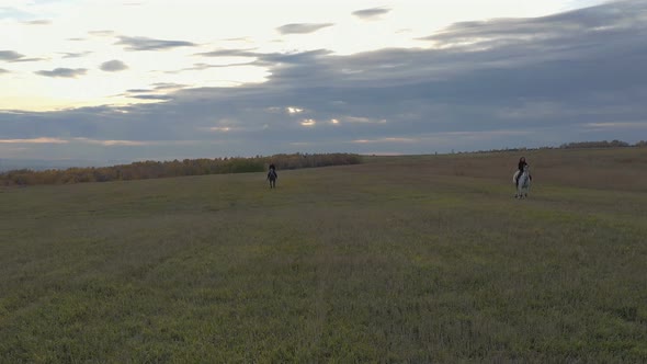 Two Women on Horseback Galloping Across the Field