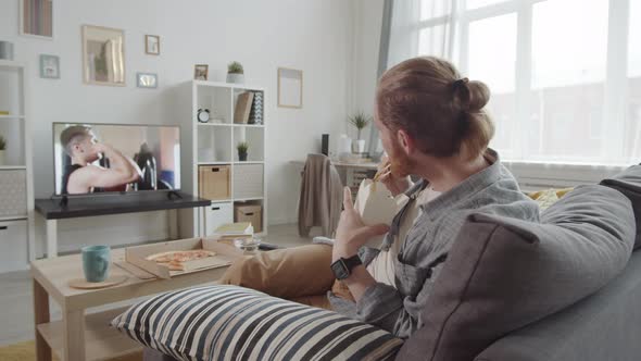 Man Eating and Relaxing on Sofa alt