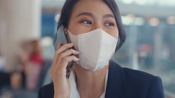 Asian business lady traveller wear suit sitting with suitcase and use smart phone chat message.