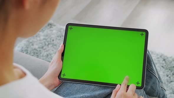 woman holding in hands a digital tablet with green screen for internet online. alt