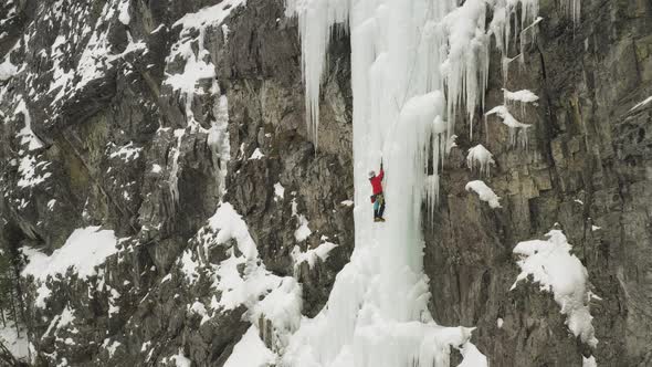 Spectacular aerial view ice climber scaling frozen cascade in Maineline, Kineo alt