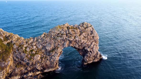 A steady panning shot filmed with a Dji Mavic of the famous, 'Durdle Door' during golden hour along alt