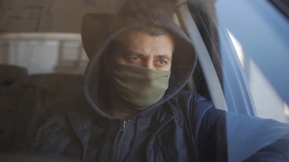 A Man Sitting in the Car Wearing Face Protective Mask Looking Outside Through the Glass Window Amid