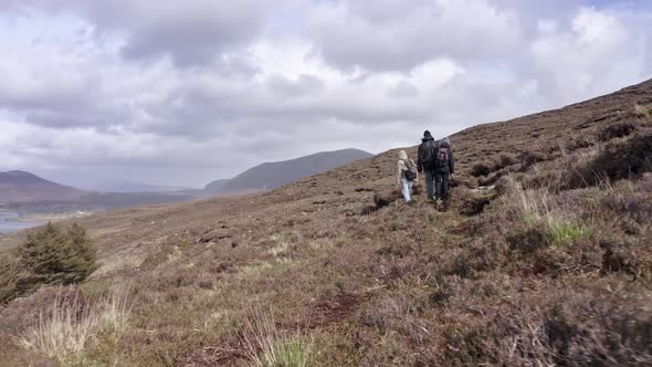 Group of Friends Walking Along Dirt Road in Irish Mountain in a Cloudy Day in Summer alt