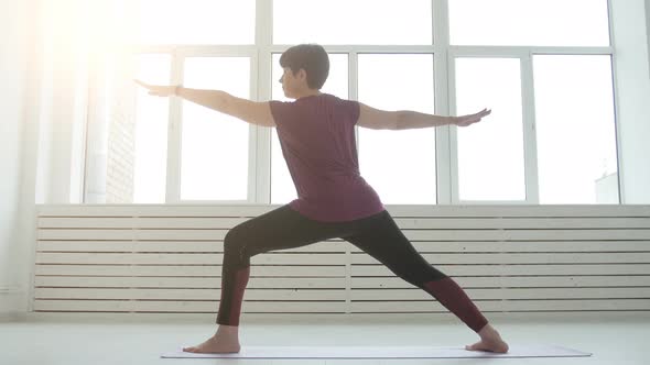 Concept of Harmony, Sport and Health. Middle-aged Woman Doing Yoga in a White Interior alt