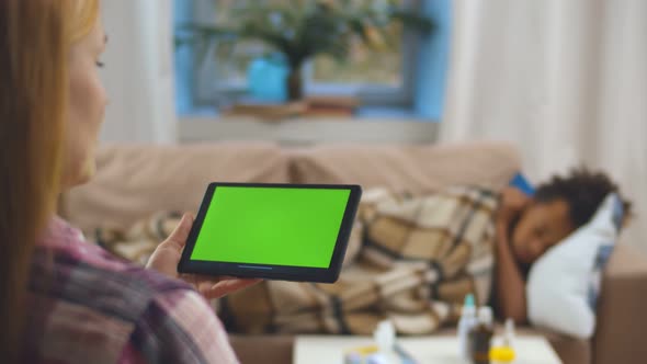 Sick Mother Talking To Doctor Online on Video Call with Sick Child Lying on Couch on Background alt