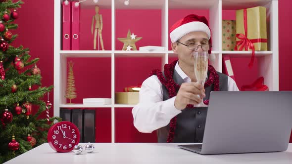 Businessman in Santa Hat Congratulates Colleagues Family Online in Office Alone