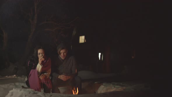 Young Couple with Hot Drinks by Fire
