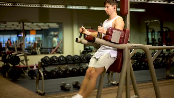 Front side shot of teen bodybuilder doing vertical leg lifts on a machine. alt
