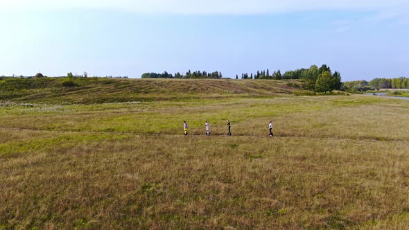 Four Teenagers Ride Across the Field Top View alt