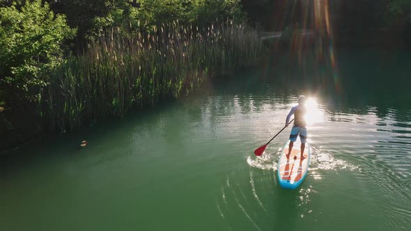 Experienced SUP Surfer Rows with Paddle on Board