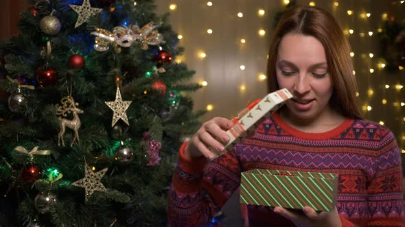Amazed Young Woman Looking at Magical Christmas Gift in the Box