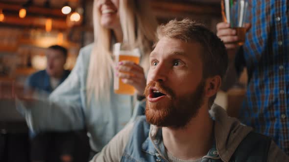 Closeup of Young Pretty Man Watching Soccer Game on TV with Friends and Getting Disappointed About alt