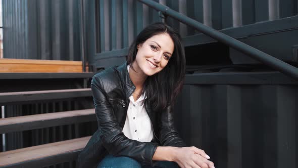 An Attractive Girl of European Appearance Looks at the Camera on the Street. alt