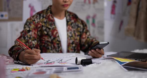 Close up hand of Asian woman fashion designer draws a sketch of women's clothing alt