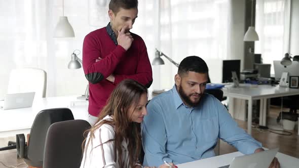 Creative Business Team Watching and Discussing Content on Laptop alt