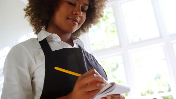 Waitress writing on notepad in restaurant alt