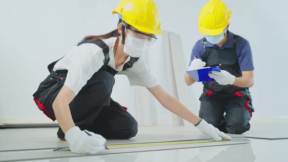 Construction worker installs laminate board on floor to renovate house wearing safety helmet. alt