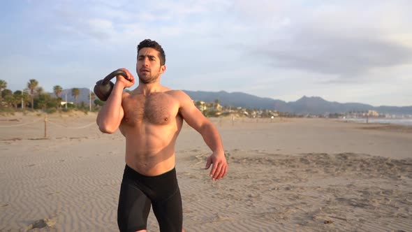 training on the beach with kettlebell and shirtless at sunrise alt