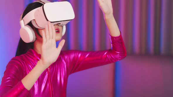 Young asian woman is using virtual reality headset. Neon light studio portrait alt