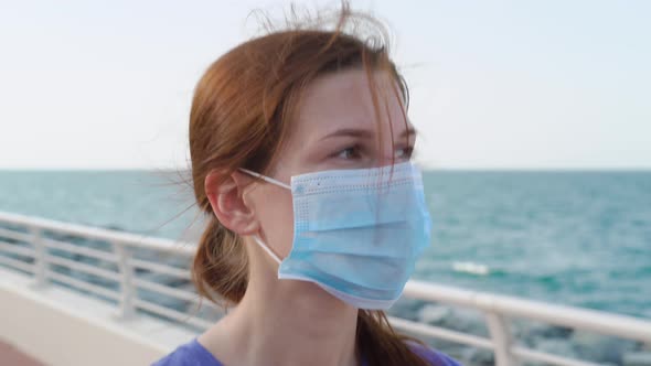 Girl Walks on Promenade in Medical Mask