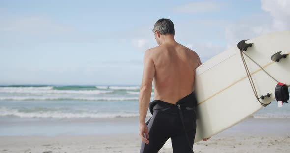 Man on beach with surfboard alt