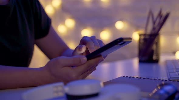 Close up shot of Female hands using smart phone in office at night