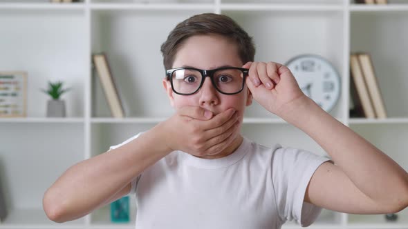 Afraid and Shocked Boy 13 Years Old in White Shirt Takes Off Glasses and Cover Mouth with His Hand alt