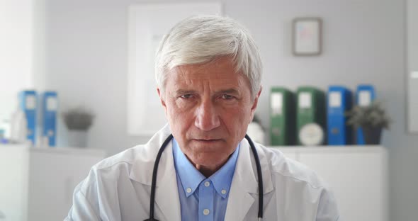 Portrait of Sad Aged Male Doctor Looking at Camera in Hospital Office alt