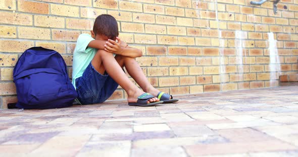 Sad schoolboy sitting alone on school ground at school, Stock Footage