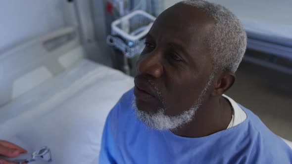 Caucasian female doctor examining throat of african american senior male patient at hospital alt