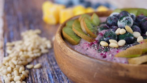 Smoothie Bowl With Fresh And Frozen Blueberries, Kiwi, Banana, Dragonfruit Powder And Pine Nuts.  alt
