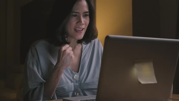 Asian business woman work overtime from home in living room at late night due to Covid19 pandemic. alt