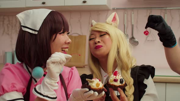 Joyful Asian Woman in Cosplay Costume Feeding Cherry Candy to Girlfriend alt