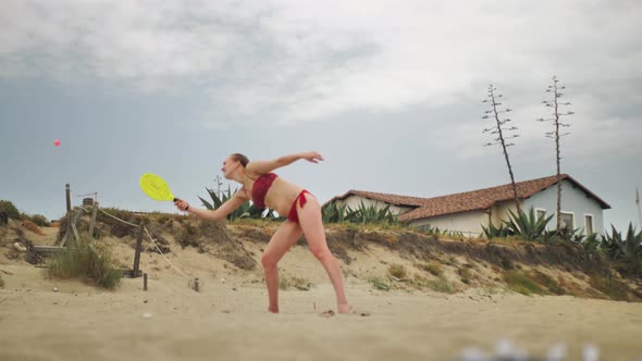 Slow Motion of Young Woman Playing Smash Ball Beach Tennis on Summer Day alt