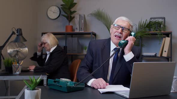 Annoyed Senior Businessman Talking on Retro Telephone Call Irritated Voice Dissatisfied with Work alt