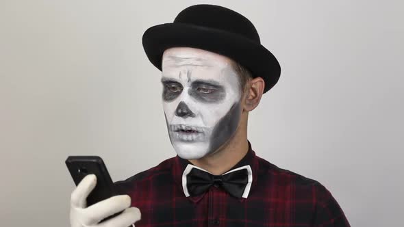 A Terrible Man in Clown Makeup and Video Chat. The Scary Clown Communicates with Friends Via Video