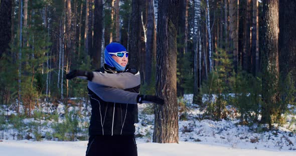 Young Man is Training Outdoors in Winter Doing Physical Exercises in Forest