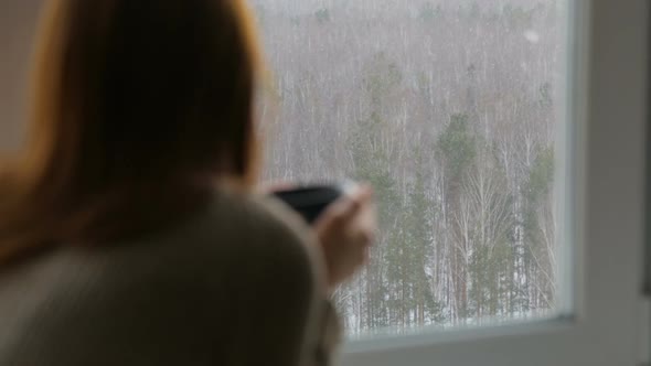 Woman drinking tea near the window