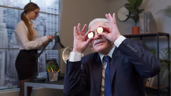 Elderly Man Boss Dancing Fooling Around Making Silly Faces with Bitcoin Coints Eyes in Office alt