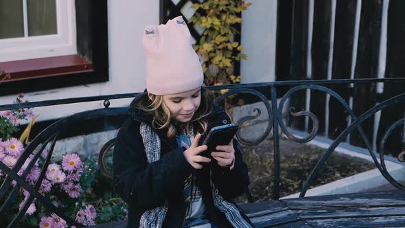 Young Child Girl Plays or Watchs Video on Smartphone