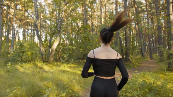 Young Woman Makes a Morning Jog in the Forest City Park