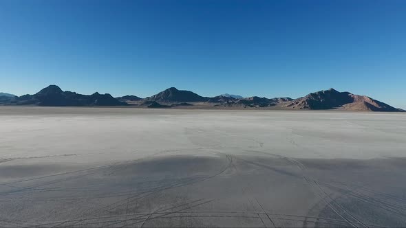 An aerial drone shot reveals smooth water covering the white slat of the Bonneville Salt Flats and d alt
