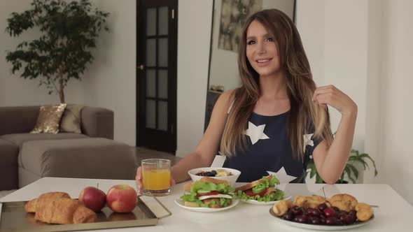 Beautiful Young Woman Sitting on Table with Appetizing Tasty Breakfast Medium Shot