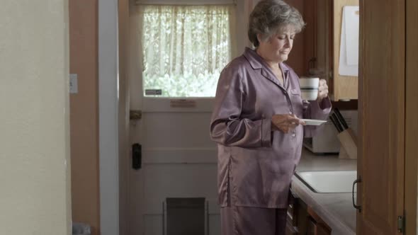 Woman drinking hot beverage in pajamas. alt