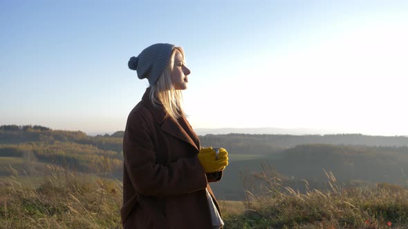 woman hold mug of tea in mountains Sudetes in November in sunset