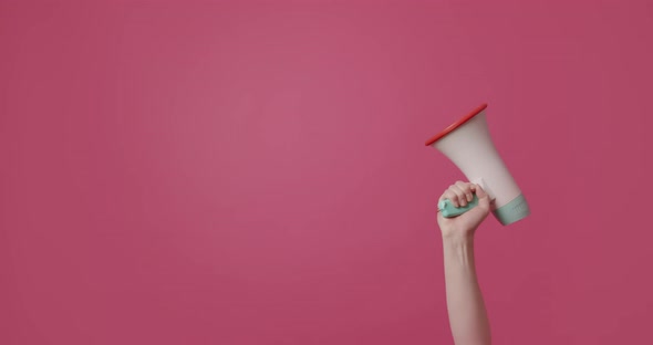 A Woman's Hands Using the Loudspeaker to Shout on Isolated Pink Background alt