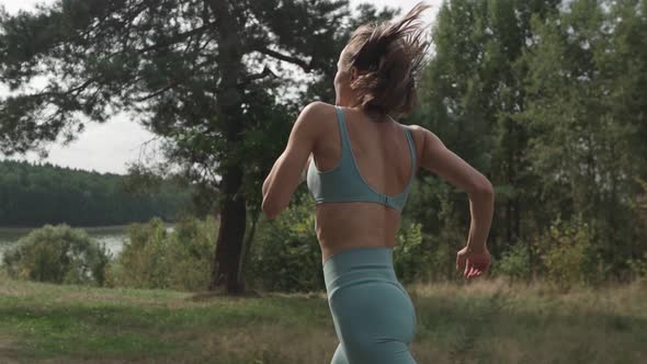 Side View of a Woman Running Uphill in a Forest alt
