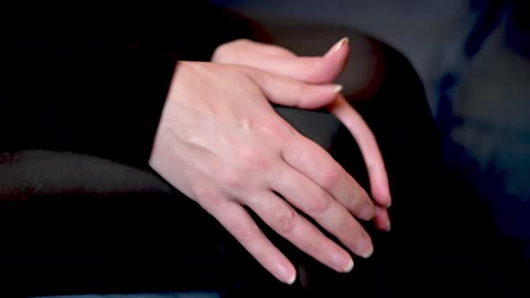 The woman rubs her knee with her hands. A woman is sitting on the couch with knee pain. alt