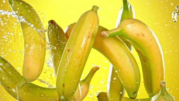 Super Slow Motion Shot of Flying Fresh Bananas and Water Side Splash at 1000 Fps alt